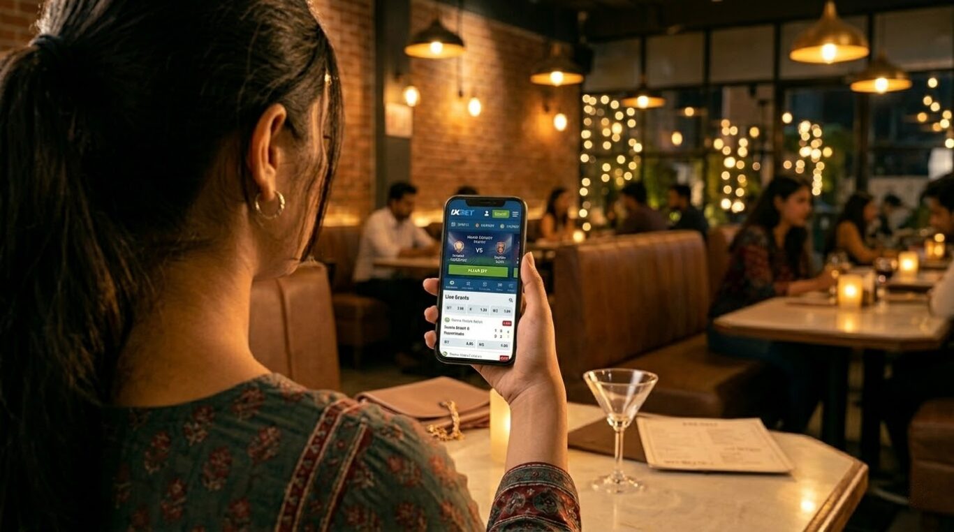 User holding a smartphone with the 1xBet Download page open in a cozy restaurant setting